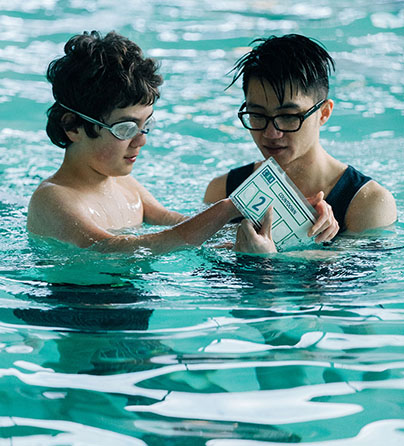 A child with autism using a countdown strip visual cue with his support worker during our I CAN Swim program.