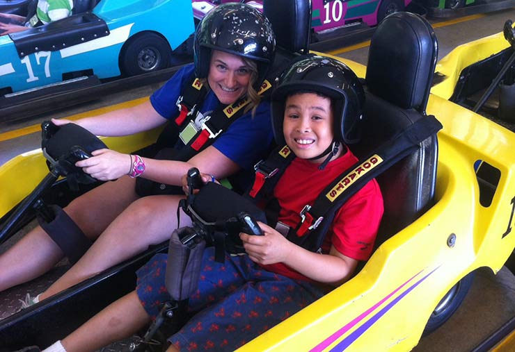 A support worker and a child with autism go-karting together in our Monthly Social Program.