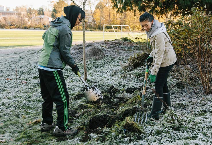 A teen with autism and a peer mentor shovel together in our CommunityWorks program.