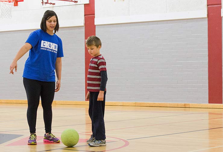 A support worker instructing soccer to a child with autism in our I CAN Play Sports program.