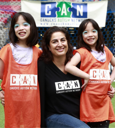 A woman with two twin girls poses for a photo.