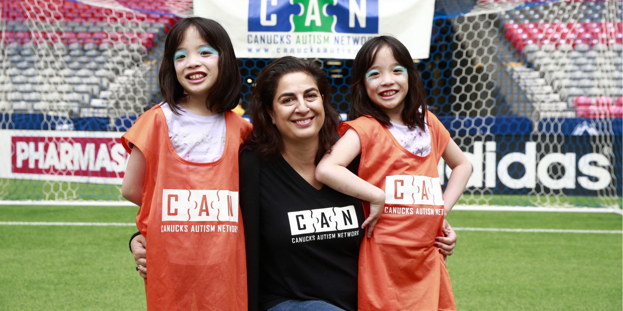 A woman with two twin girls poses for a photo.