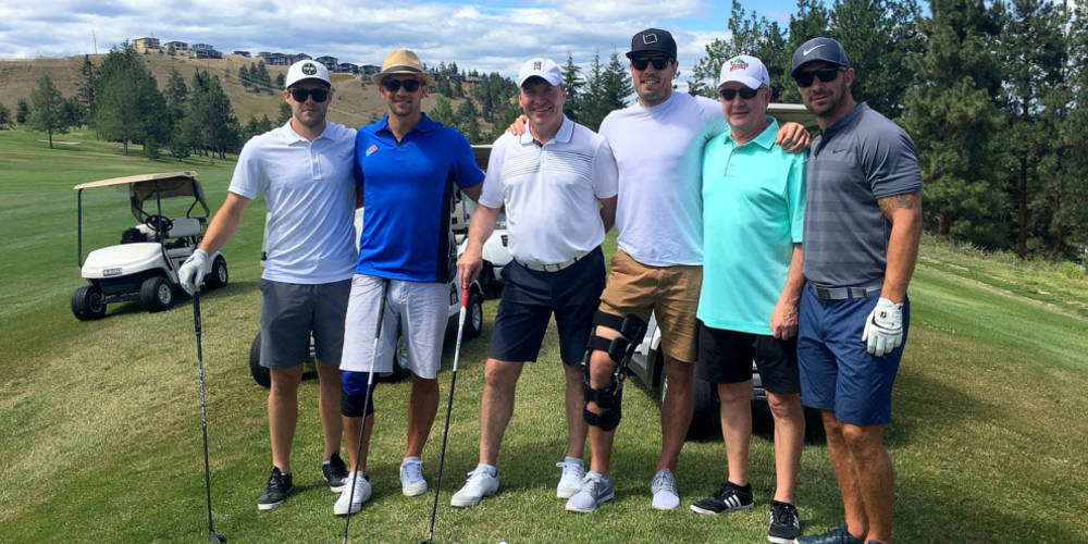 Six golfers pose for a photo on the golf course.