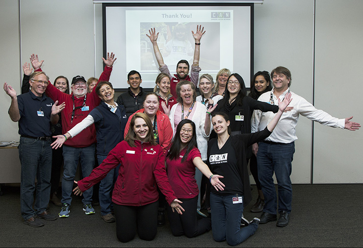 A group of adults cheering with a Canucks Autism Network staff.