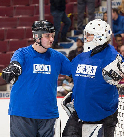 A male coach talking with an ice hockey goalie on the ice.