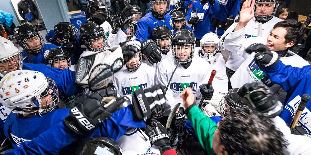 CAN ice hockey participants cheer with coach.