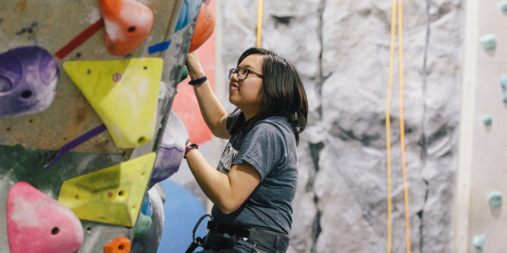 A young adult woman rock climbing