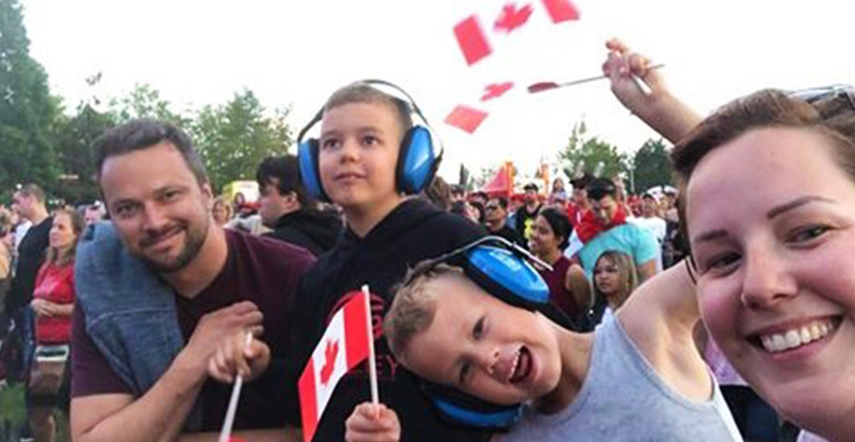 Family at a Canada Day celebration with Canadian flags and noise-cancelling headphones